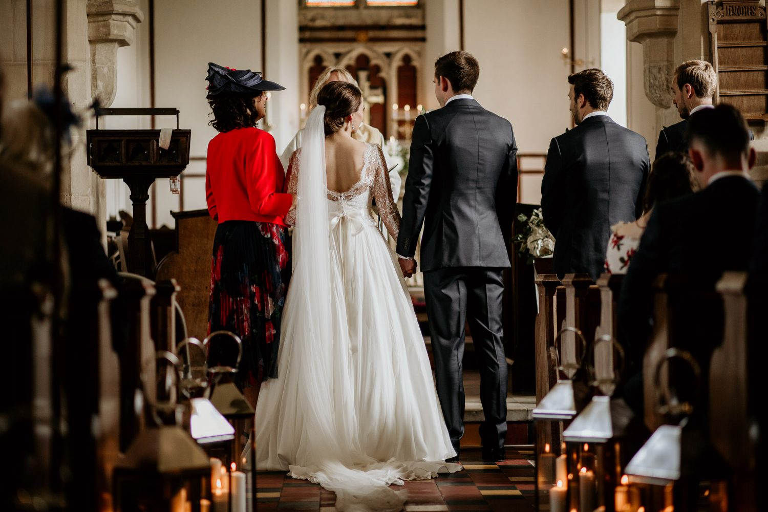 luxury manor house hotel wedding bride ad groom hold hands at the church alter