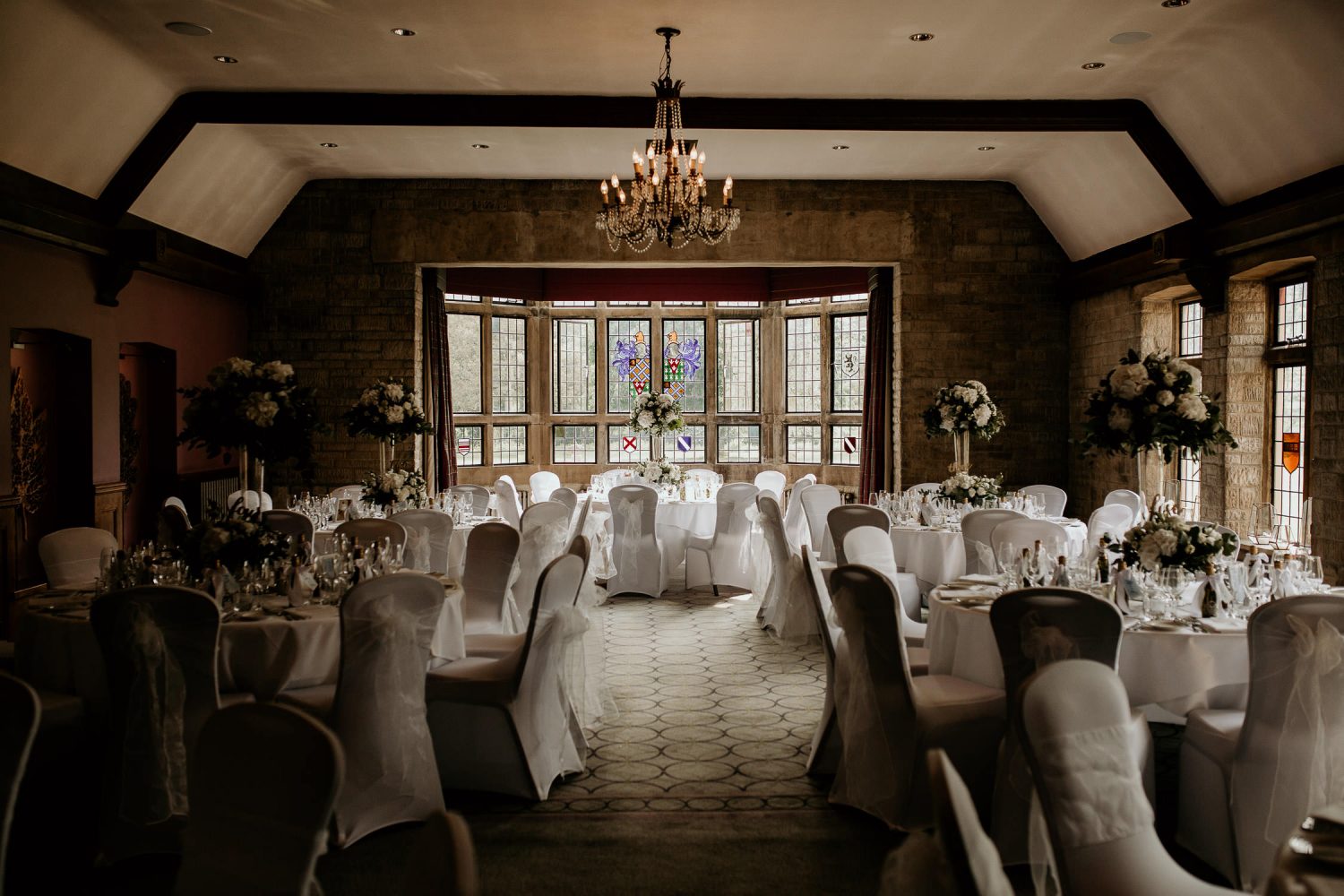 luxury manor house hotel wedding empty reception venue with white decorations and large floral centrepieces