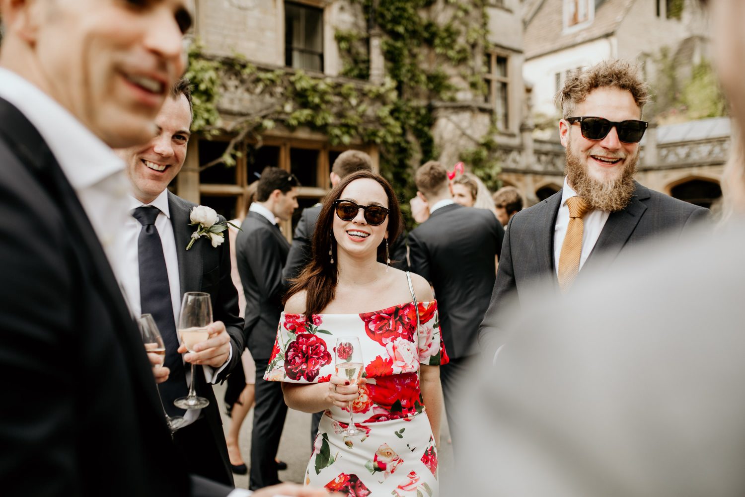 luxury manor house hotel wedding photo of guests laughing outside of venue in the sun