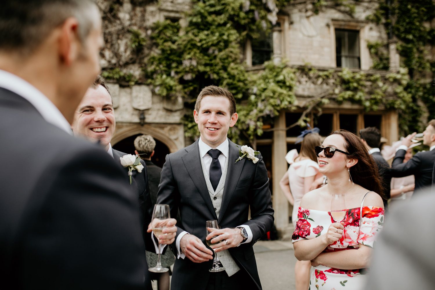 luxury manor house hotel wedding groom and guests talking side of venue in the sun