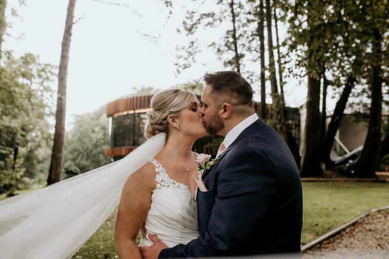 photo of bride and groom kissing outside of wedding venue