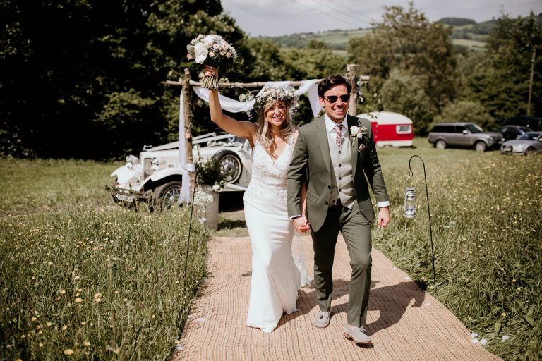 fun boho tipi wedding Hereford smiling bride and groom arriving at the reception venue in luxury vintage car in background