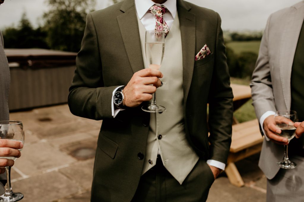 groom holding glass of champagne during groom prep