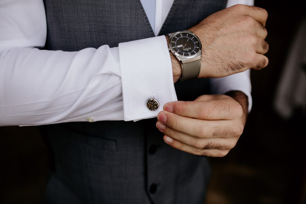 close up of groom getting ready for wedding showing grey trousers and waistcoat, white shirt and higend watc and cufflinks