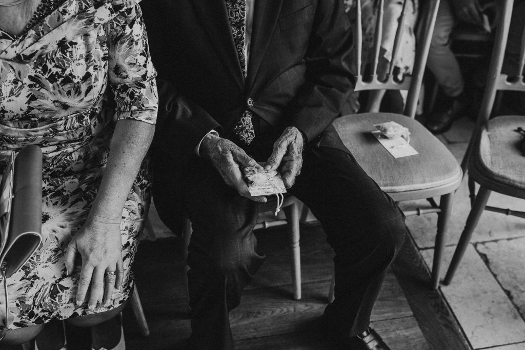 sentimental close up wedding guests in suit holding small ornate bag
