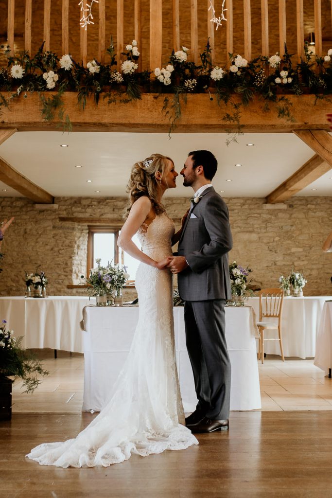 bride and groom stand hand it hand at the alter in luxurious beamed barn conversion wedding venue