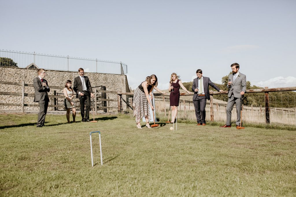wedding guests play croquet in the sunshine outside of luxurious barn conversion wedding venue