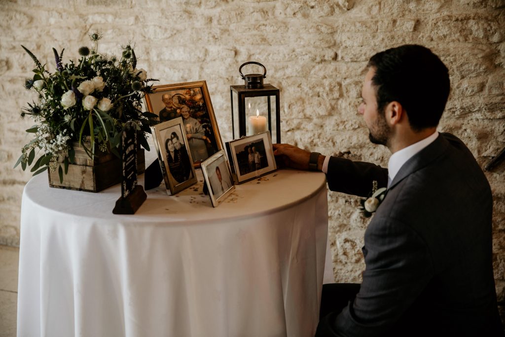 sentimental photo of groom looking at photos of family members on in memory of table