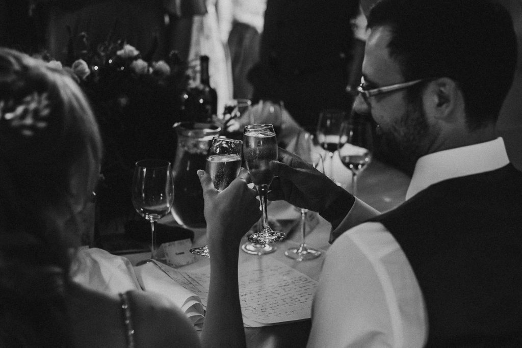 black and white photo of bride and groom drinking champagne