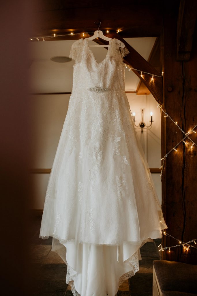 wedding dress hung up on beams with fairy lights