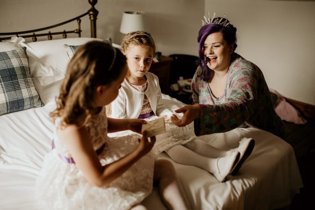 smiling alternative bride gives gives to young bridesmaids