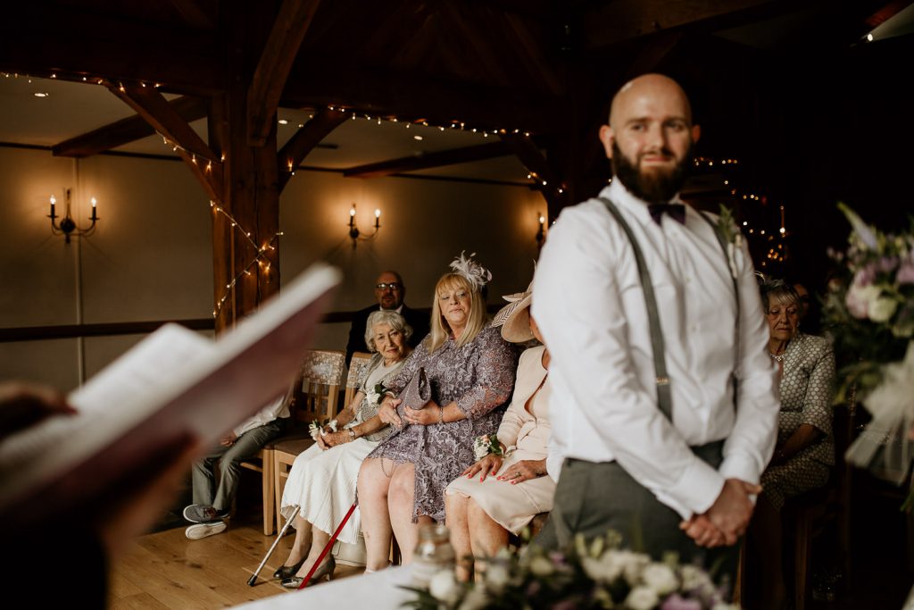 wedding guests watch on as groom stands proudly ready to take vows