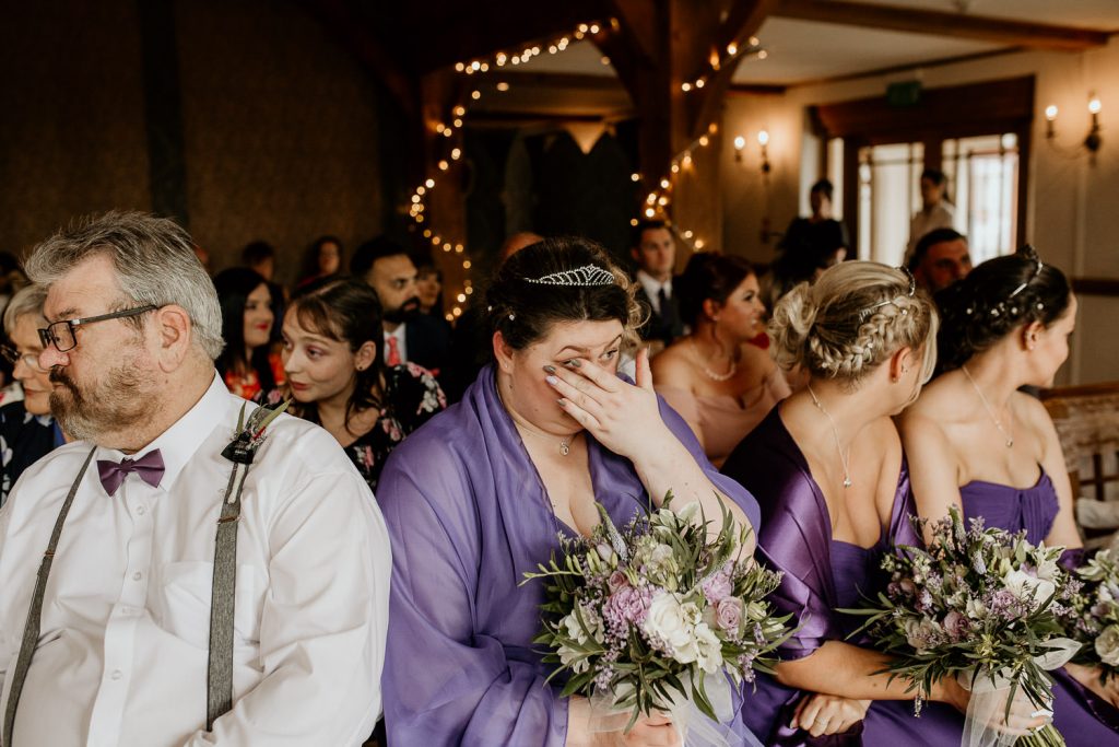 emotional photo of crying bridesmaid surround by other seated wedding guests