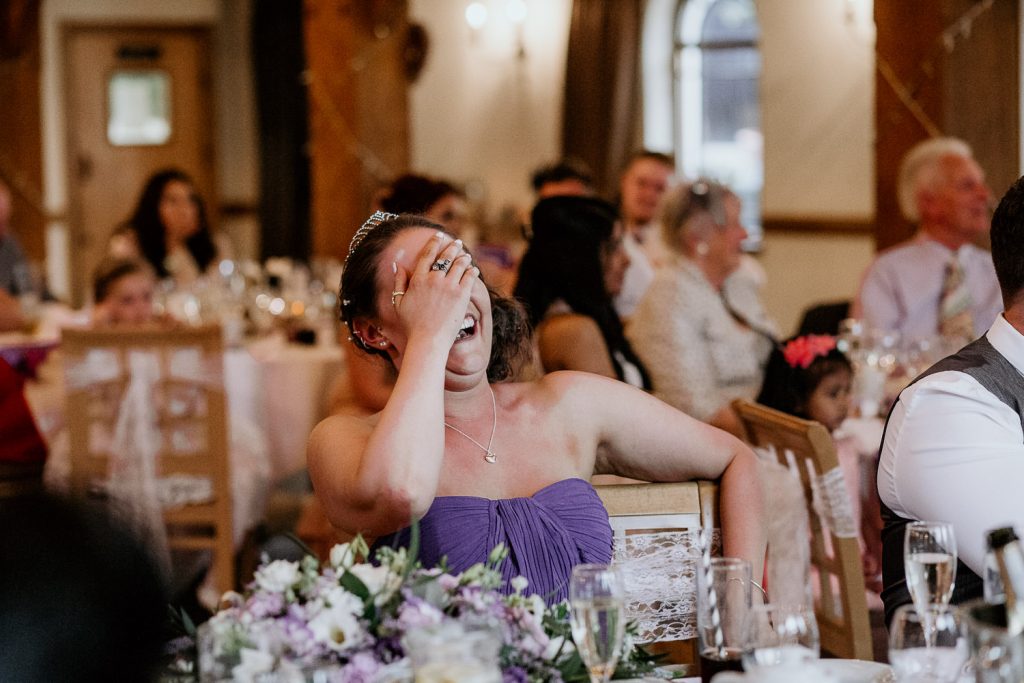 bridesmaid in purple dress laughing during speeches
