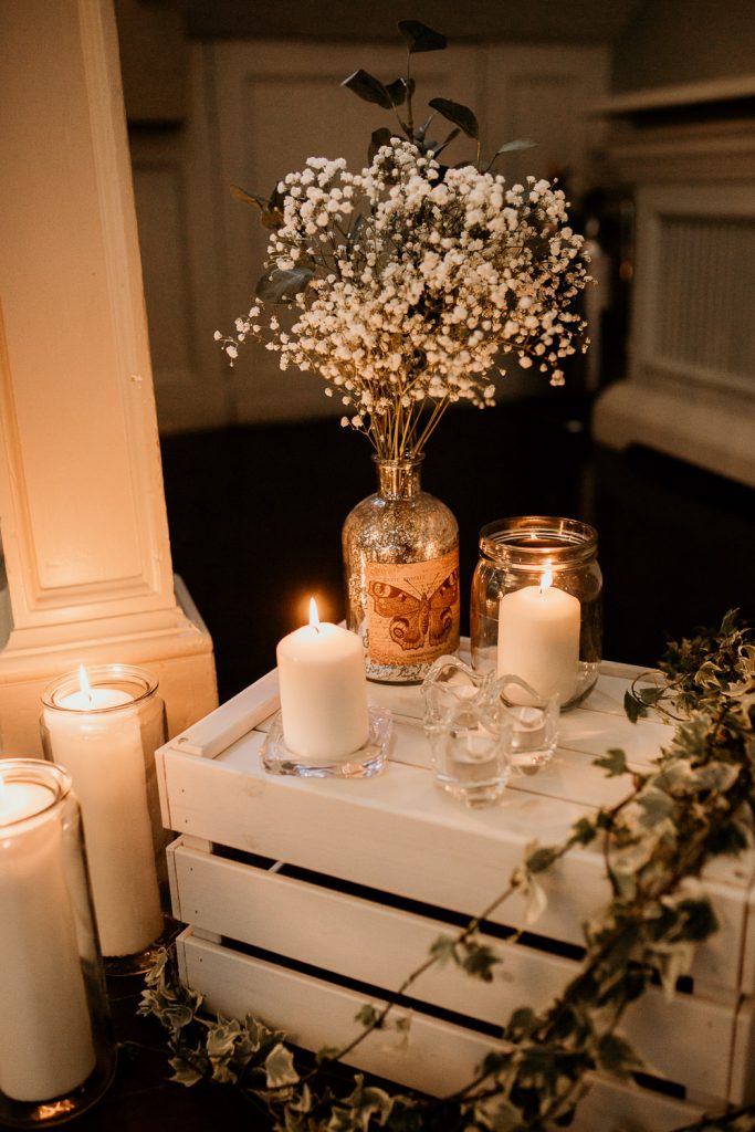 minimalistic and chic personalised wedding decoration white vintage box, white candles, ivy and delicate white flowers in a butterfly vase