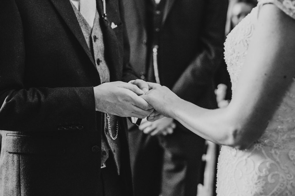 black and white close up of bride and groom holding hands during the wedding ceremony