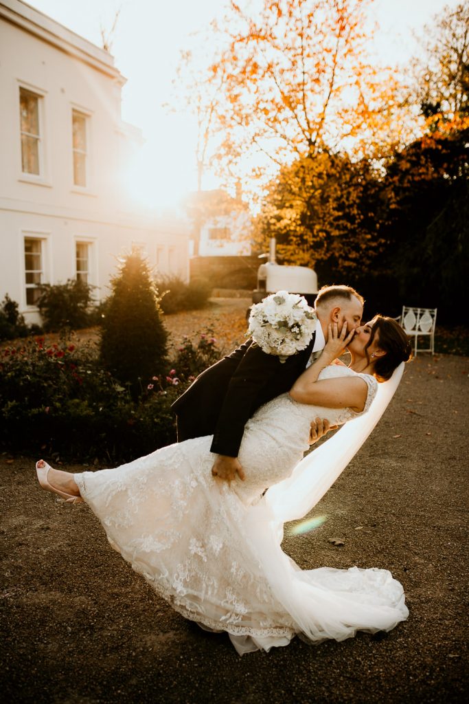 golden hour photo of bride and groom kissing and dancing outside in front of the setting sun