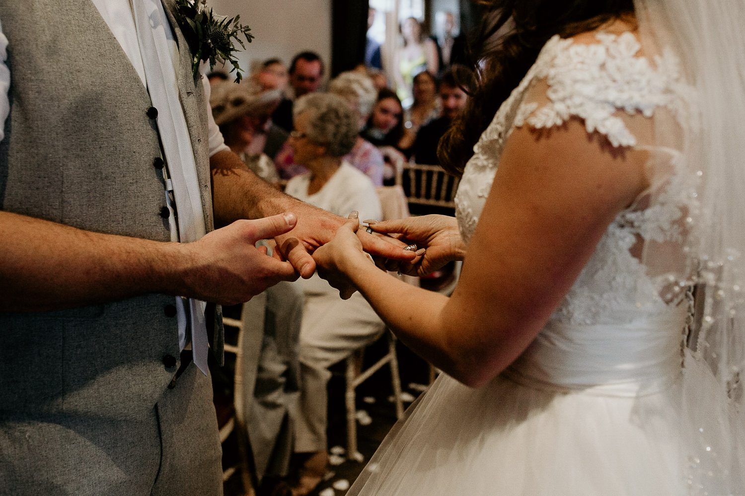 close up photo showing the bride putting the wedding ring on the grooms finger