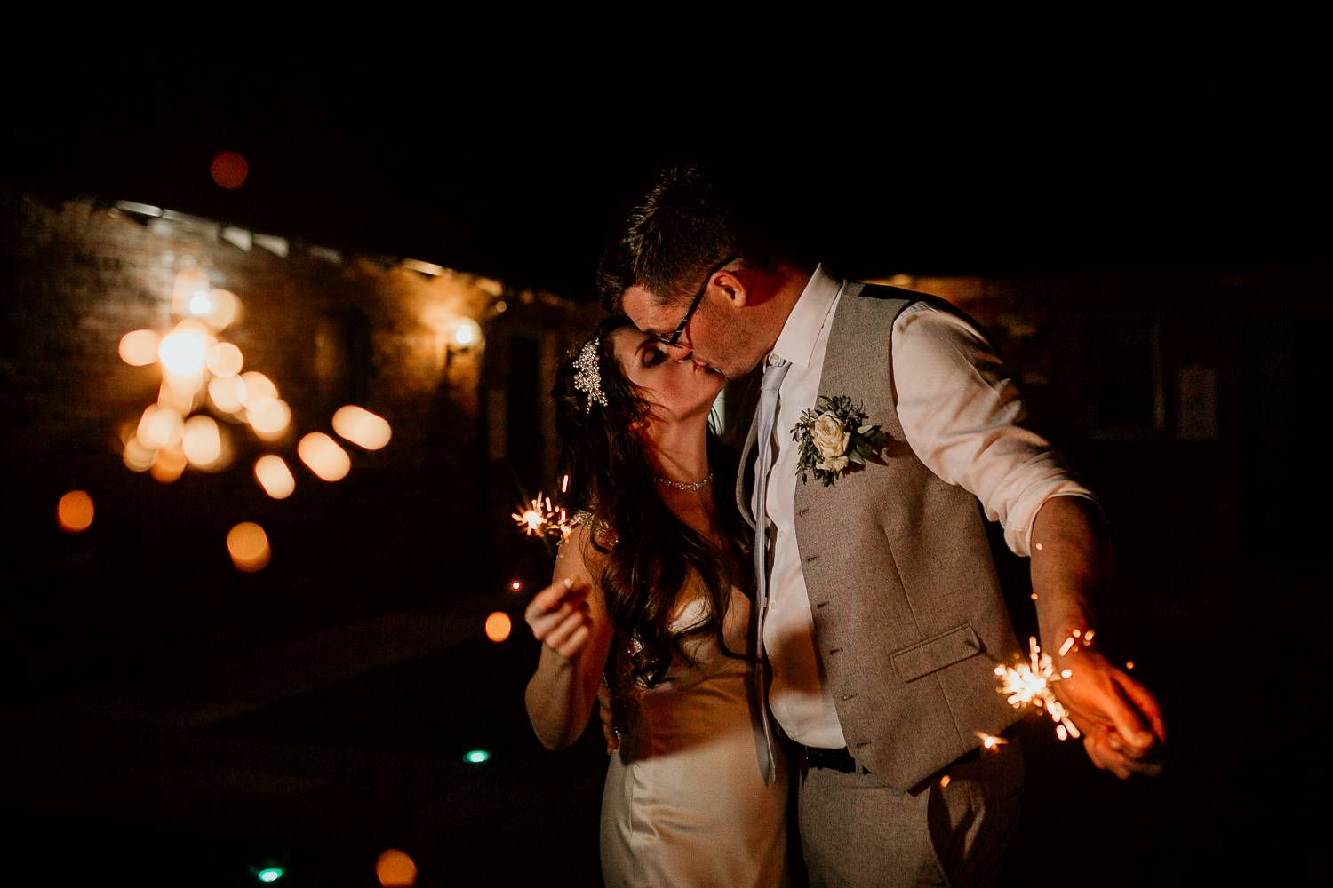 photo of the bride and groom kissing and holding sparklers