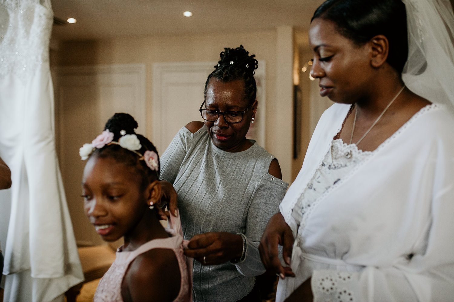 bride and family help young bridesmaid get ready on the morning of the wedding