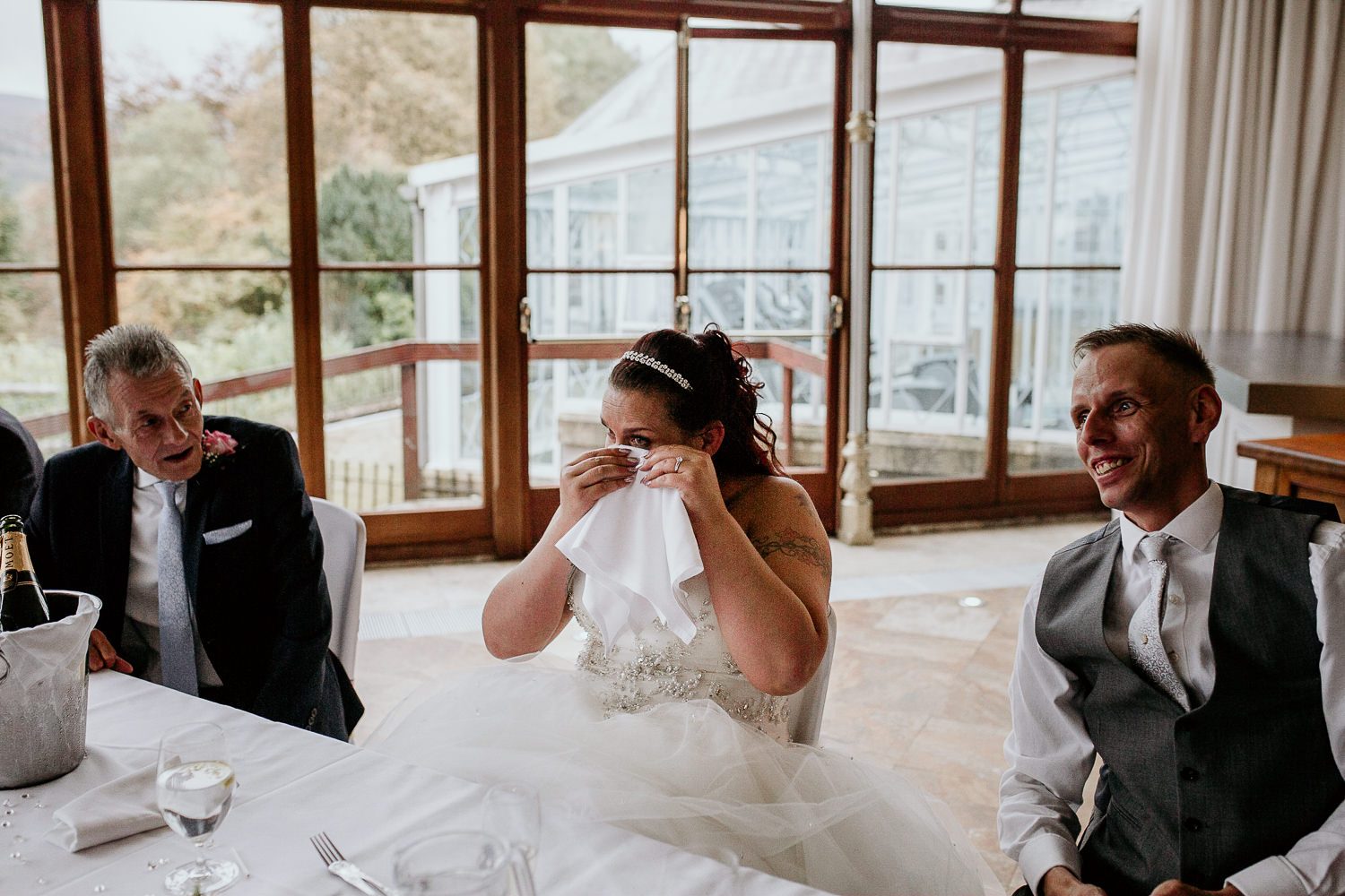 emotional bride cries during speeches whilst groom laughs beside her