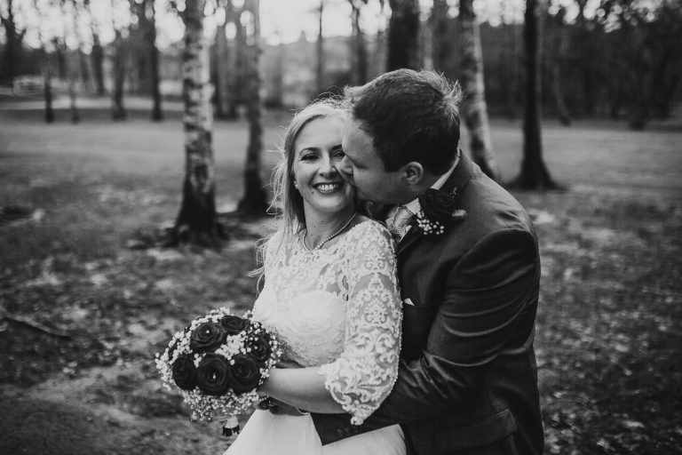 groom kissing bride on cheek at winter wedding in vale resort
