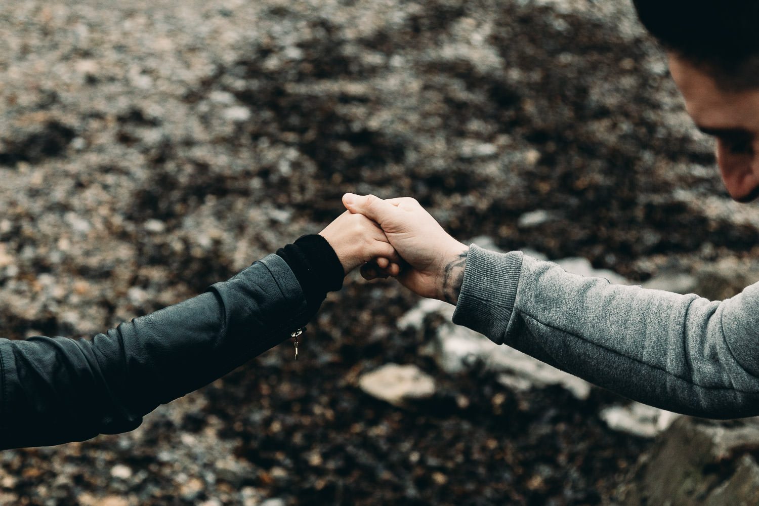 Bride and groom walk hand in hand seaside engagement shoot close up of hands