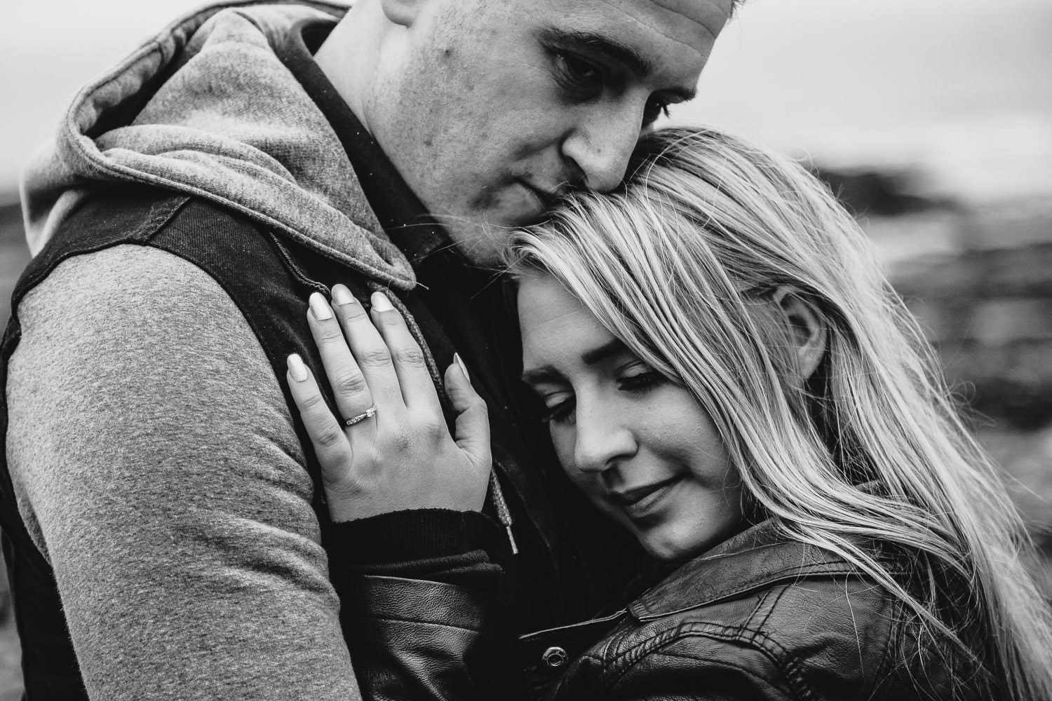 close up of bride and groom cuddling on seaside engagement shoot black and white