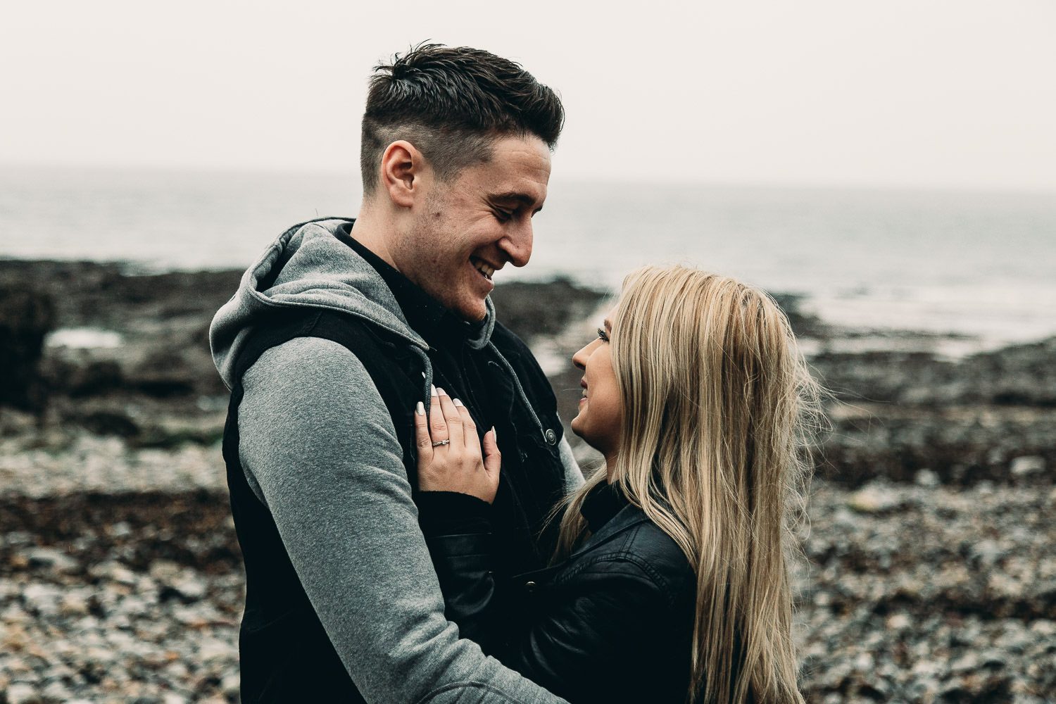 bride and groom laugh and cuddle on seaside engagement shoot