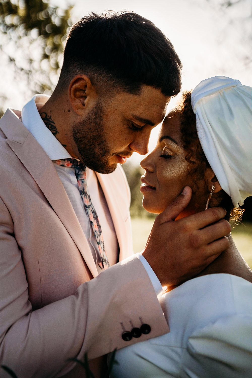 Black Bride with Head Wrap and Cheek highlighter and Groom in Pink Blazer Embracing
