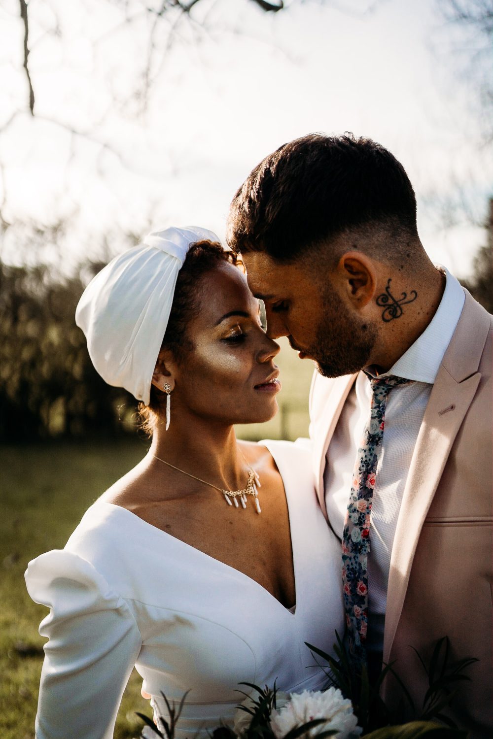 Black Bride with Head Wrap and Cheek highlighter and Groom in Pink Blazer Embracing