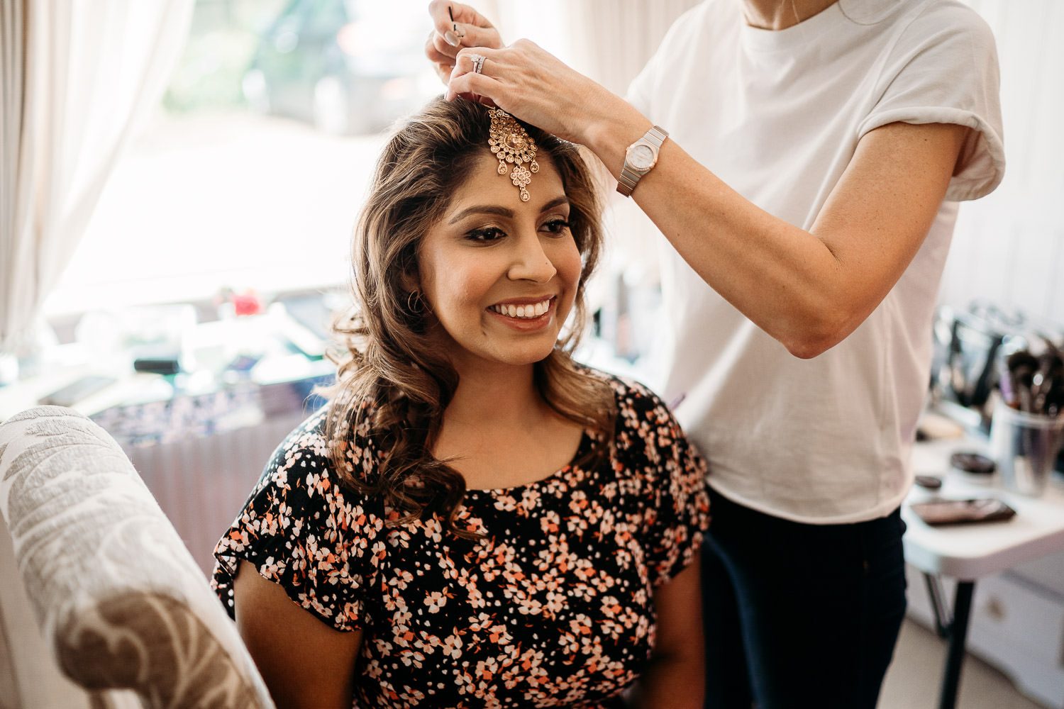 hairdresser placing maang tikka on bride's head