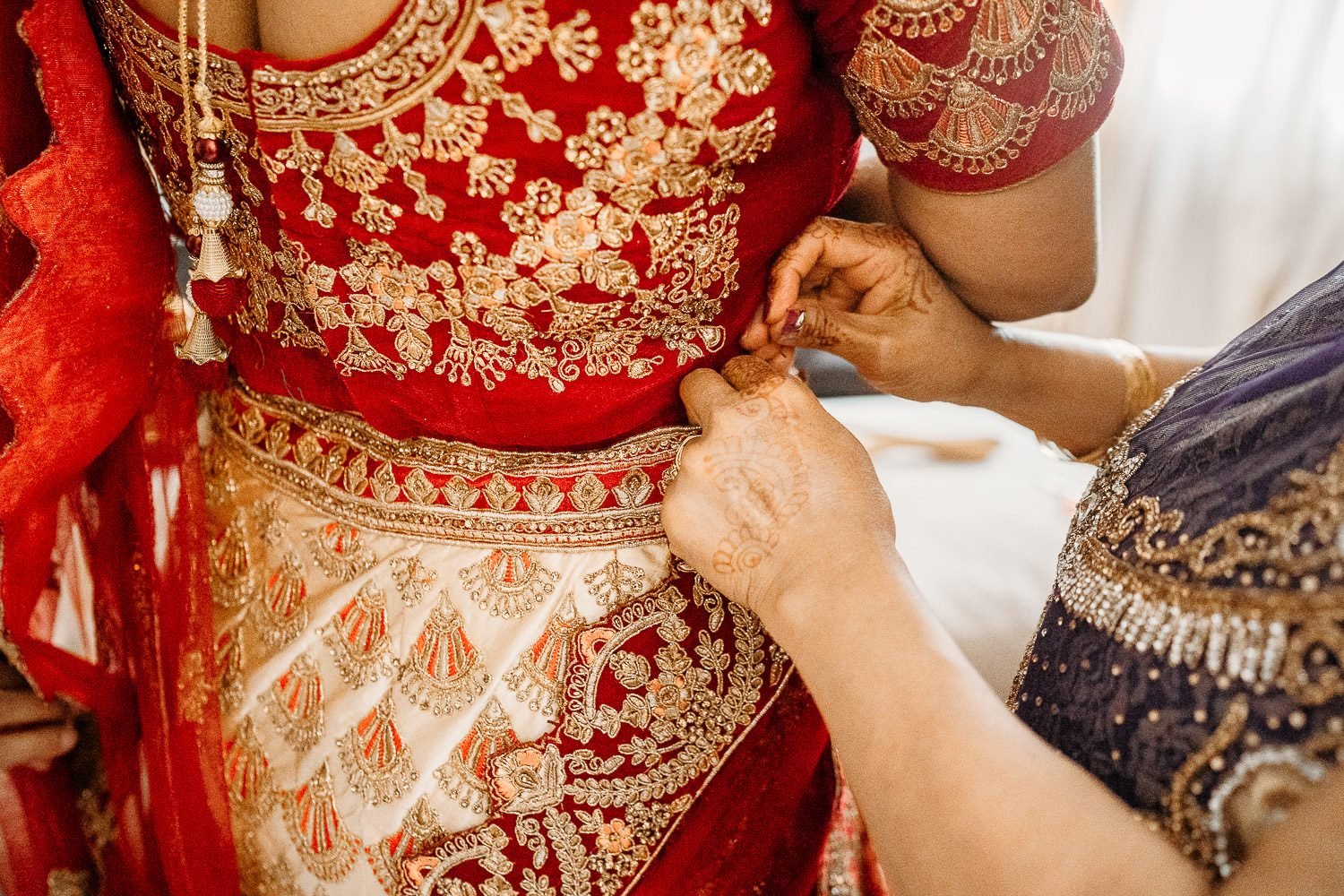 brides mother pinning red sari for bride