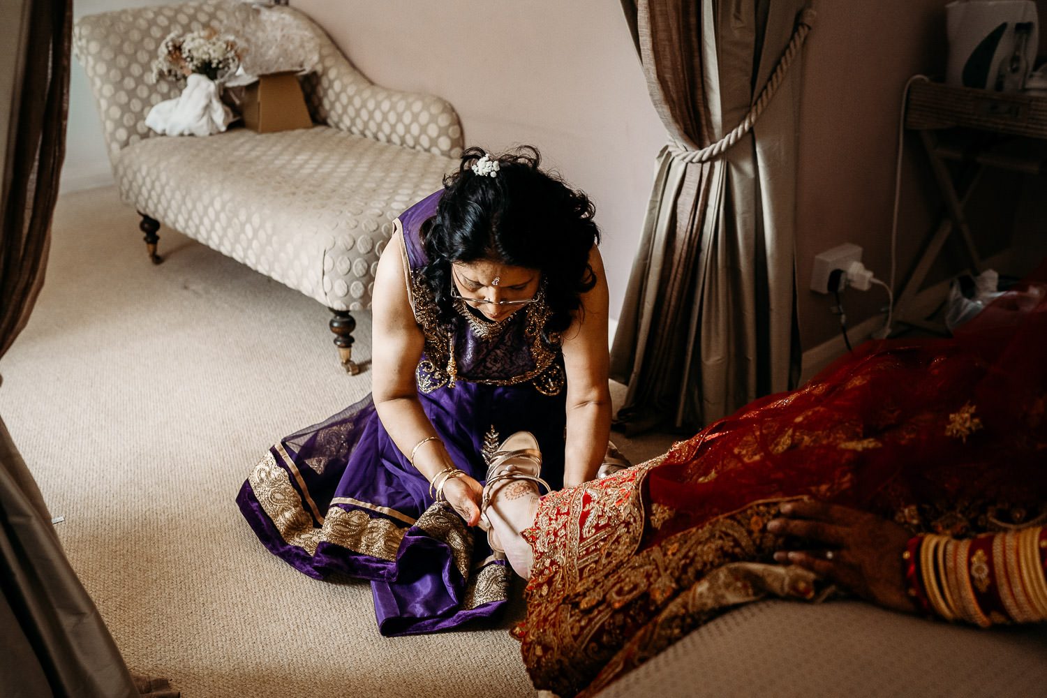brides mother helping bride put on wedding shoes