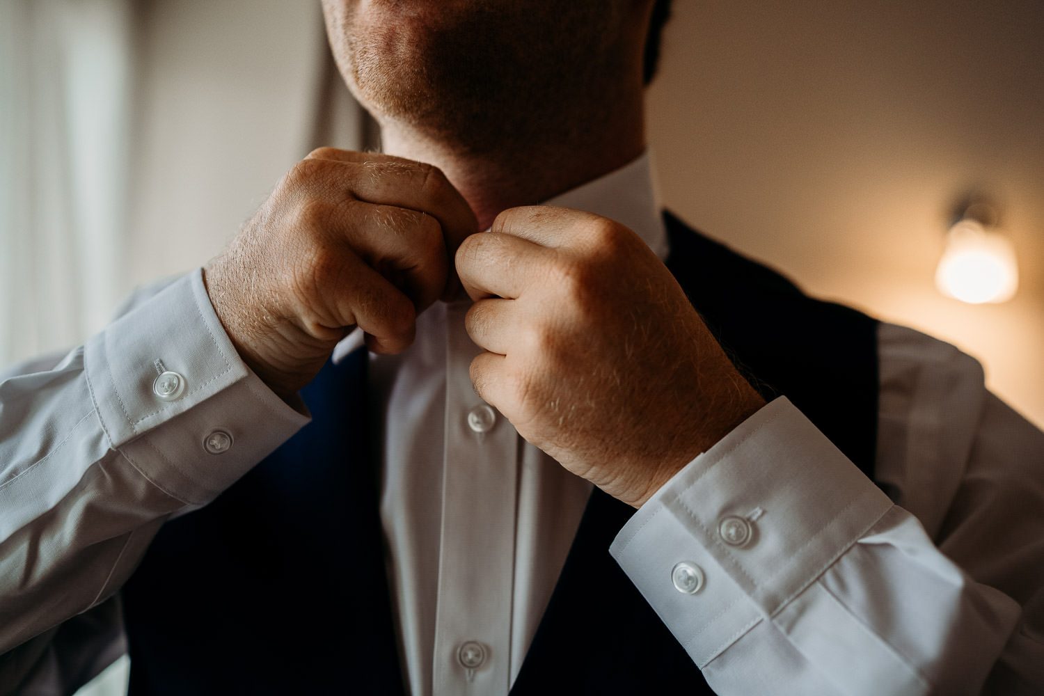 groom doing up his shirt during morning preparations