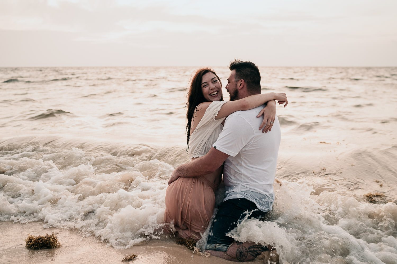 bride and groom laughing while in sea in mexico