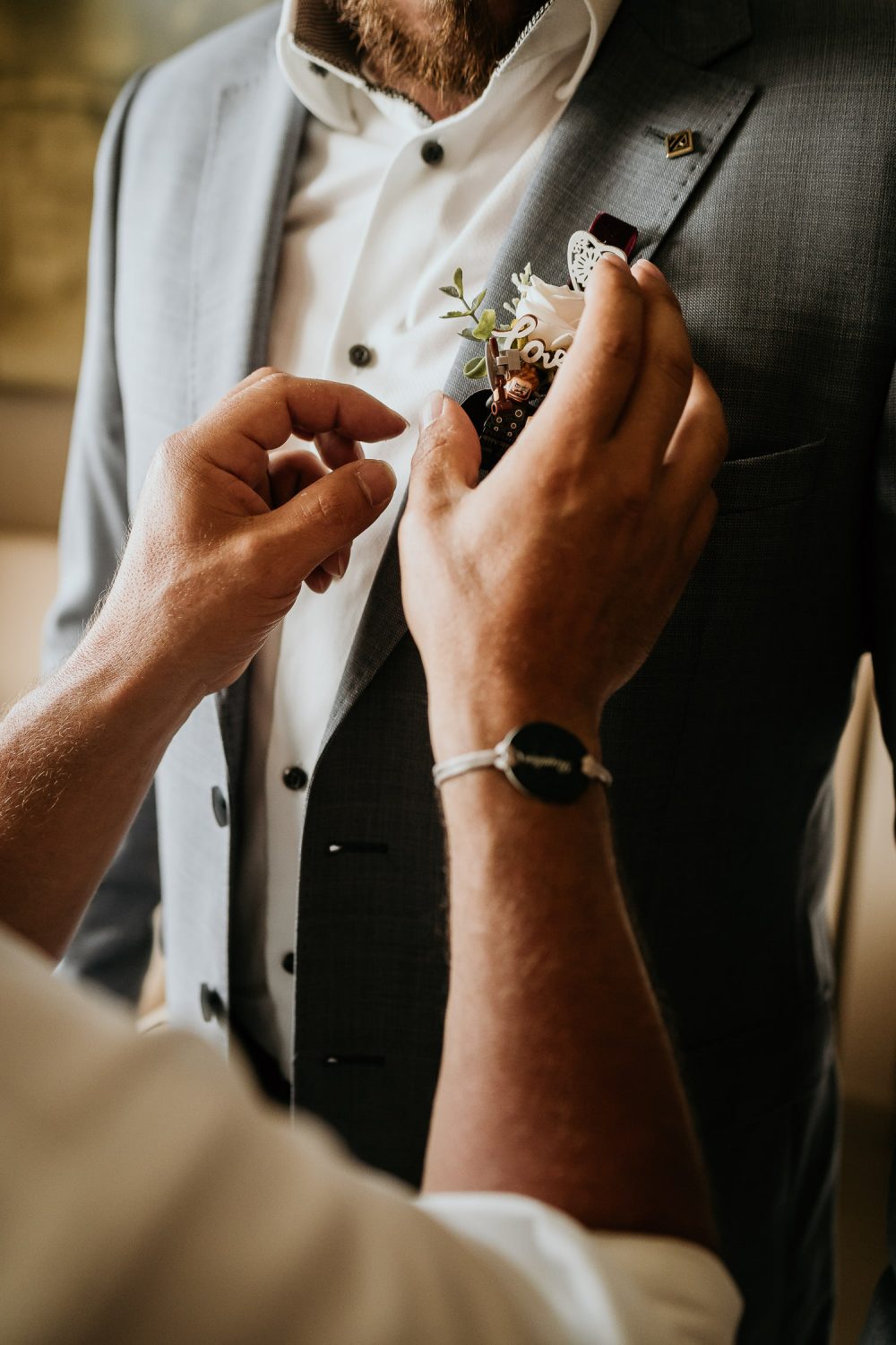 grooms father pinning grooms buttonhole on suit jacket
