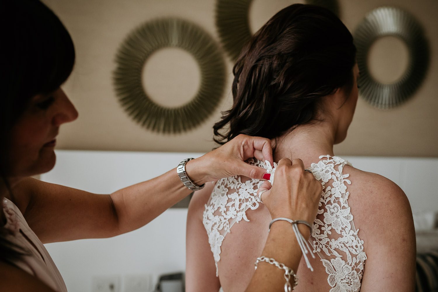 mother of bride adjusting buttons on brides wedding dress