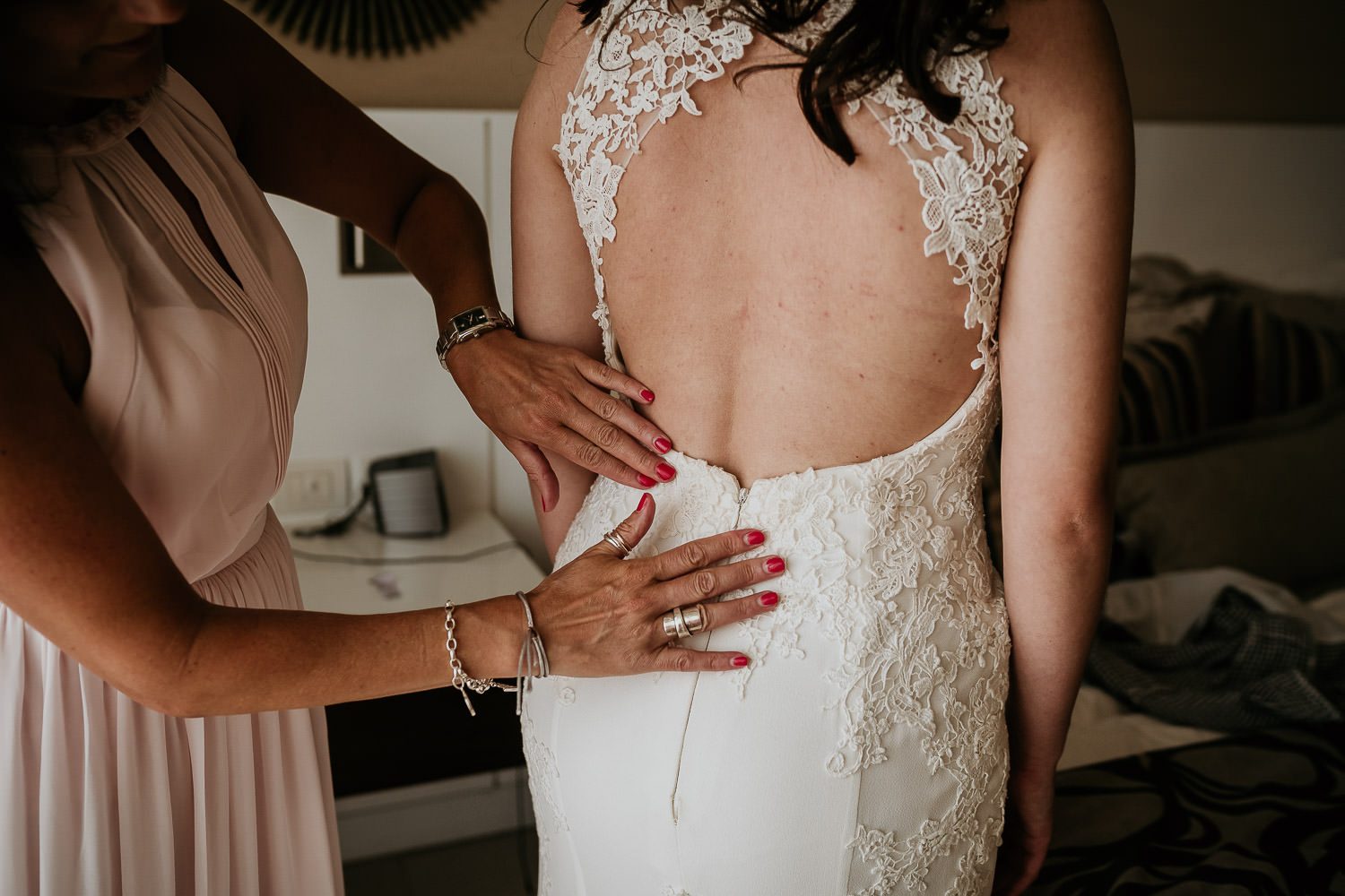 mother of bride adjusting lace on brides wedding dress