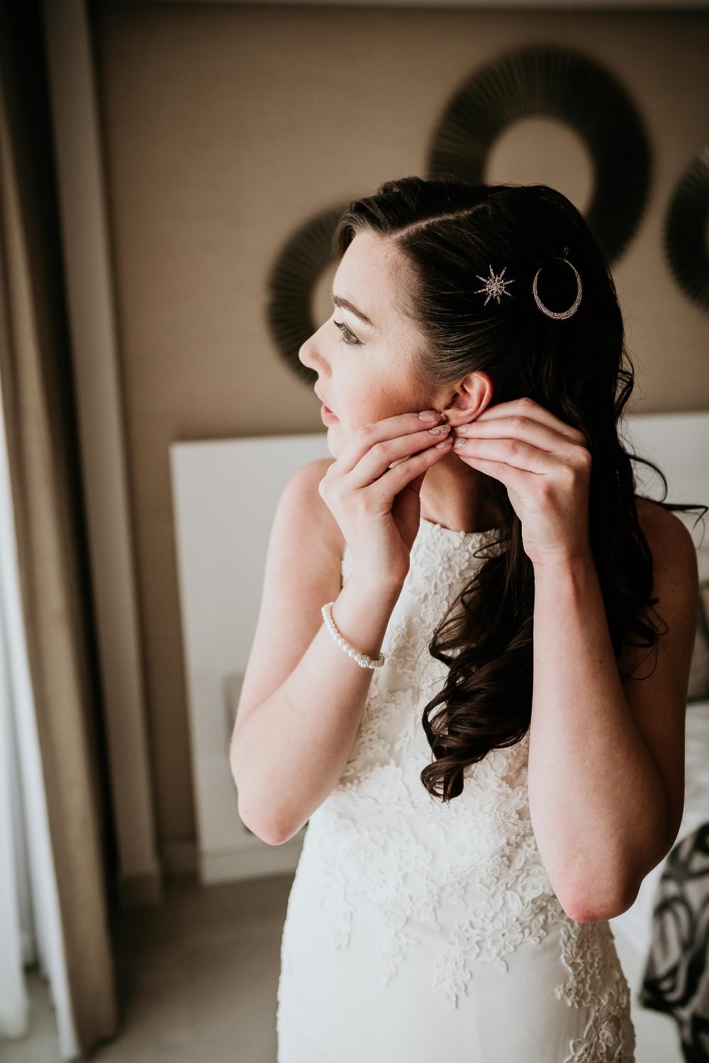 bride putting in earrings before wedding 