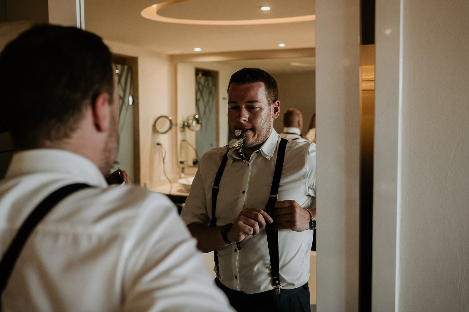 best man adjusting braces in mirror