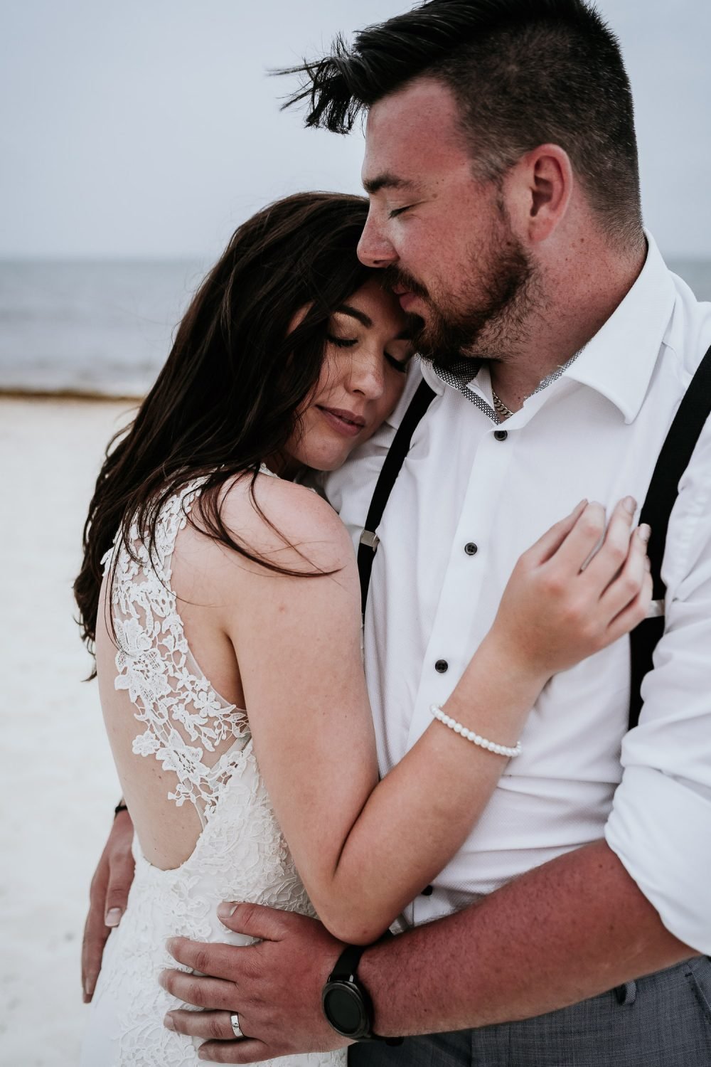 bride and groom cuddling on beach in cancun
