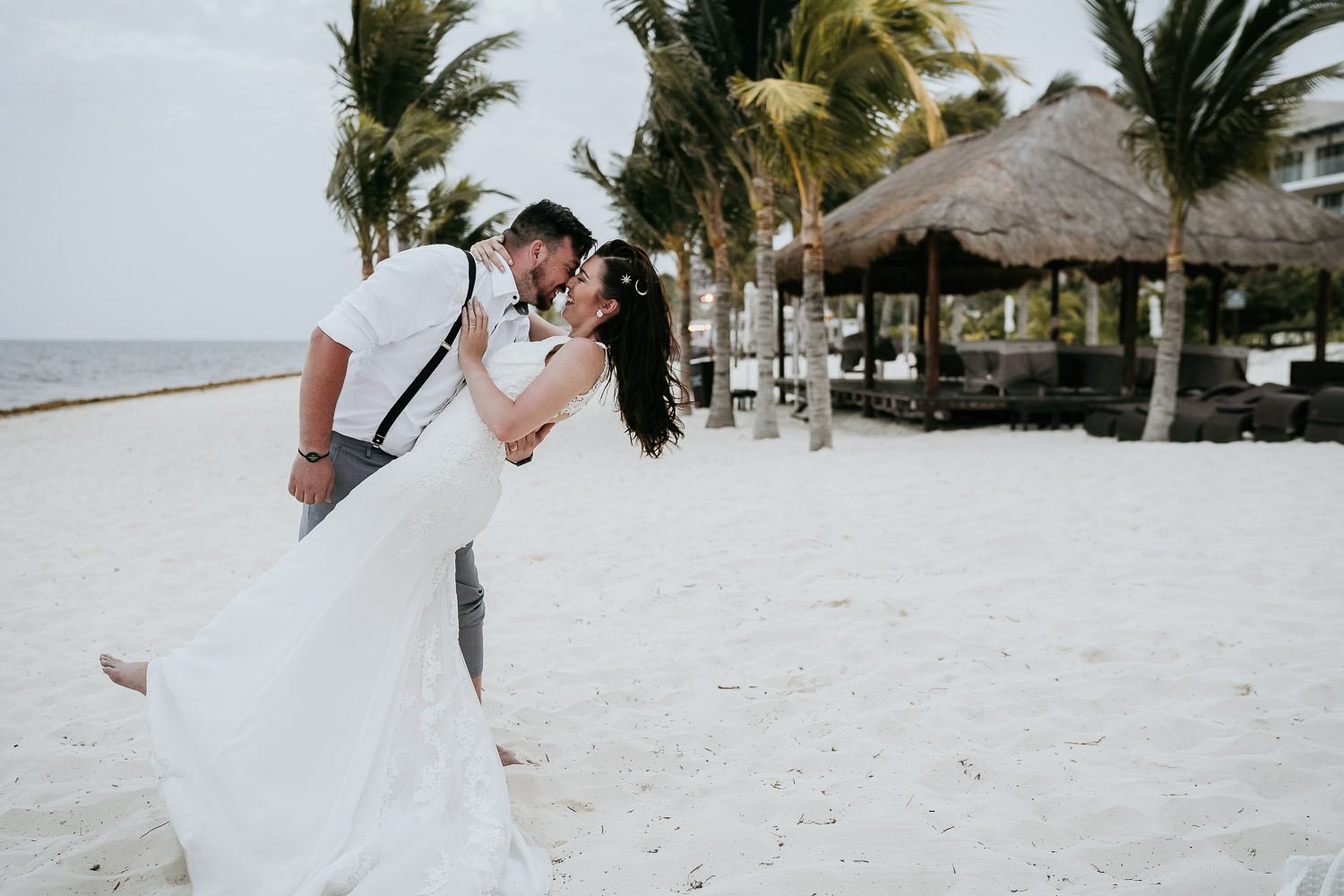 groom kissing bride on beach in cancun