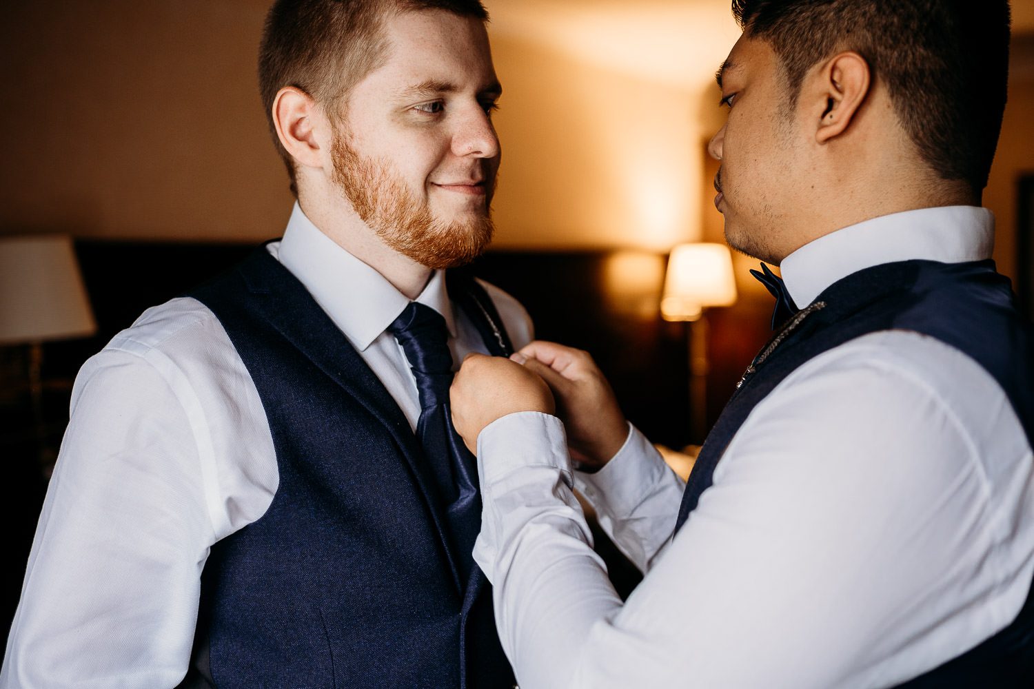 best man helping groom with pheasant feather buttonhole