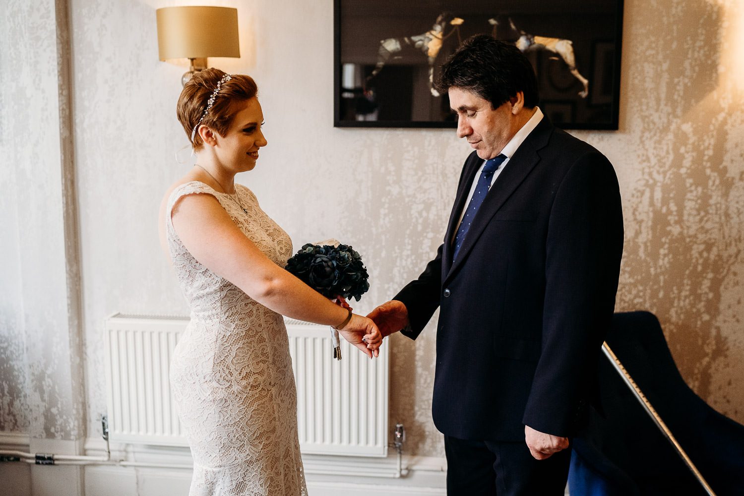 father of bride holding brides hand during first look at mercure elcot wedding