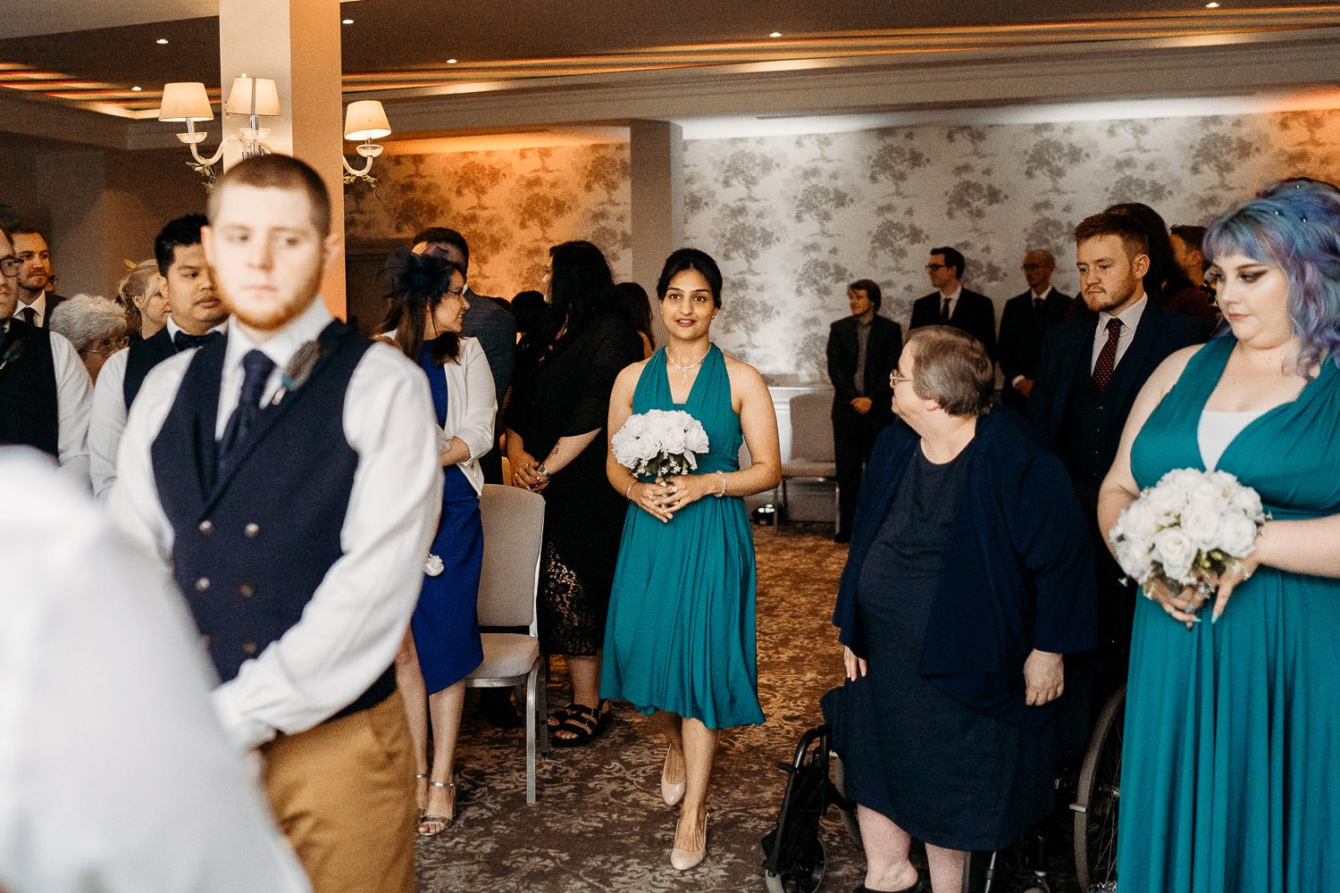 bridesmaid in blue dress walking down the aisle at mercure elcot park wedding