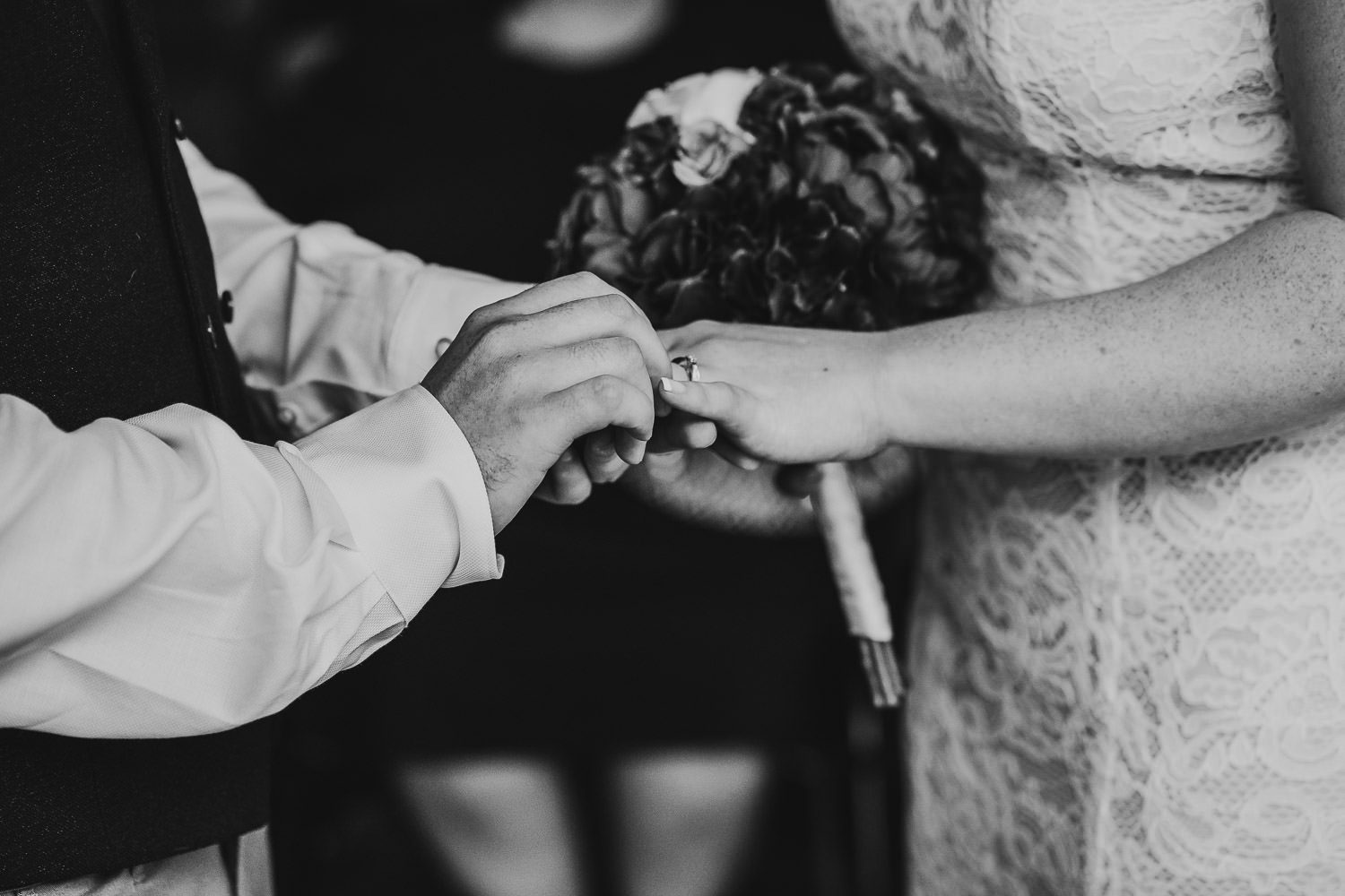 groom putting ring on brides finger during wedding ceremony at mercure elcot hotel
