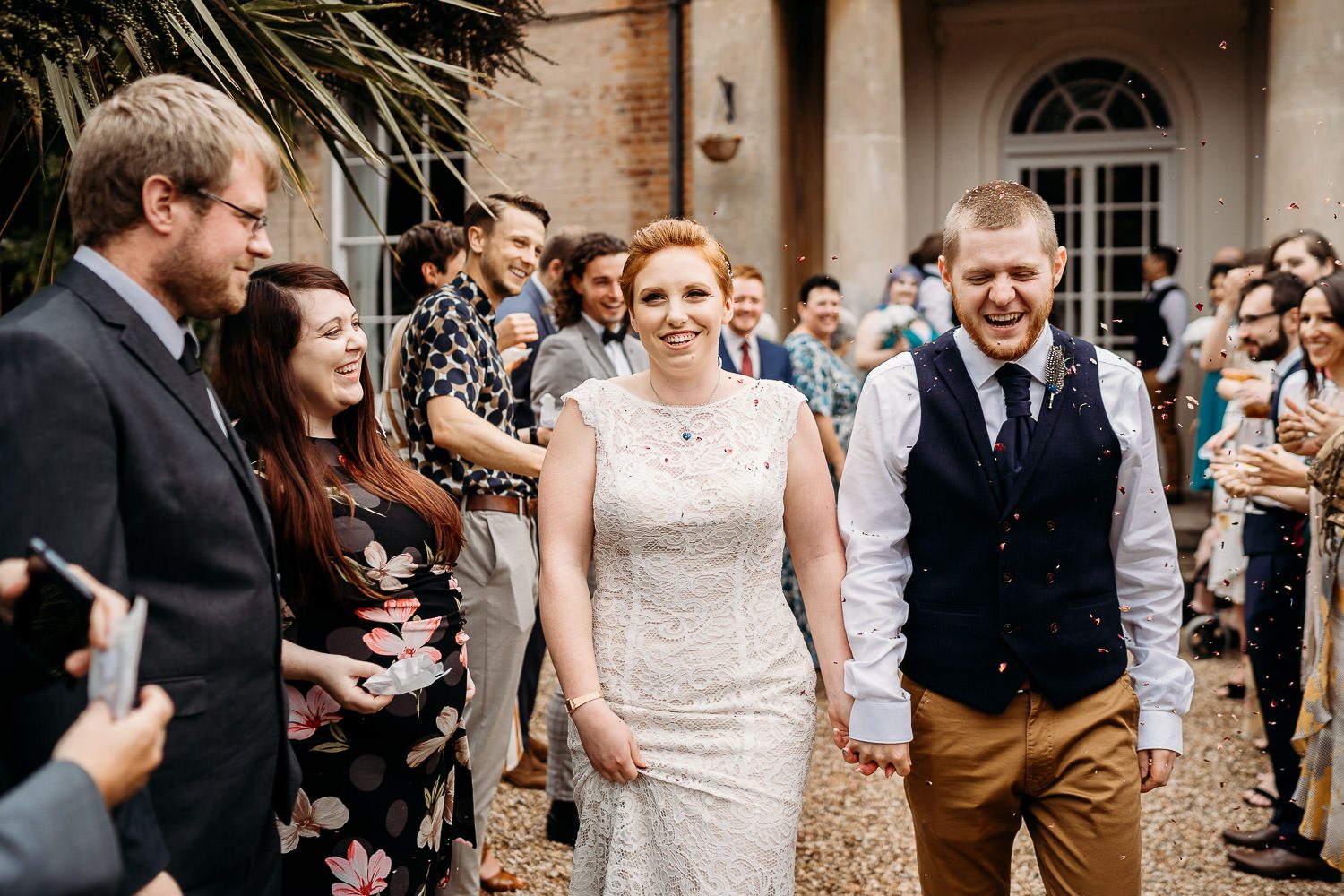 alternative bride and groom having bright flower petal confetti thrown at them