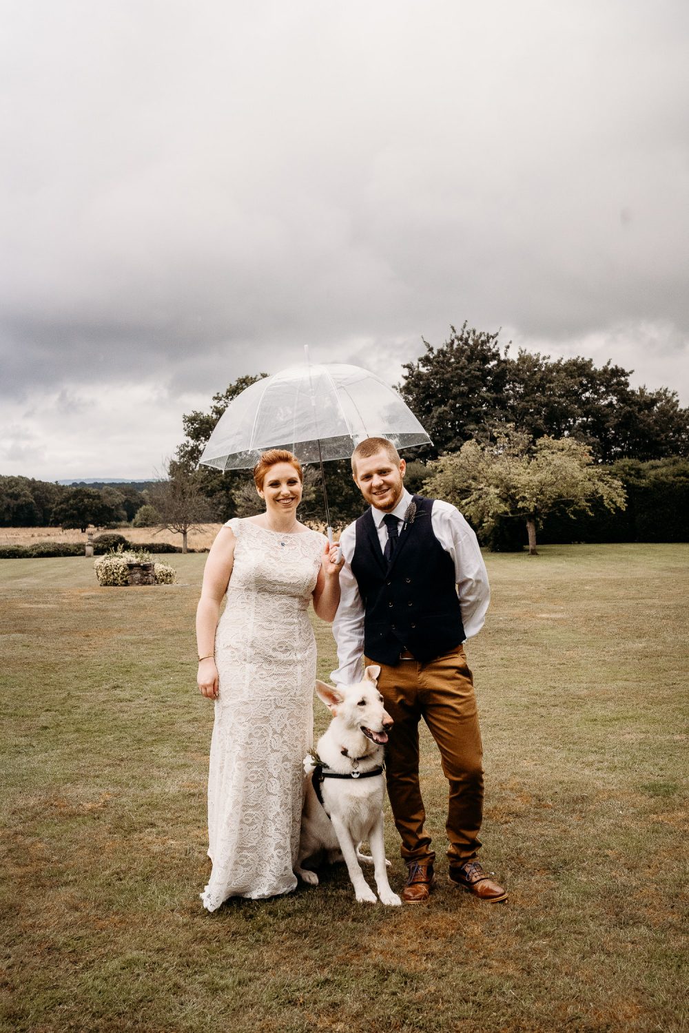 bride and groom cuddling their white german shepherd dog on wedding day