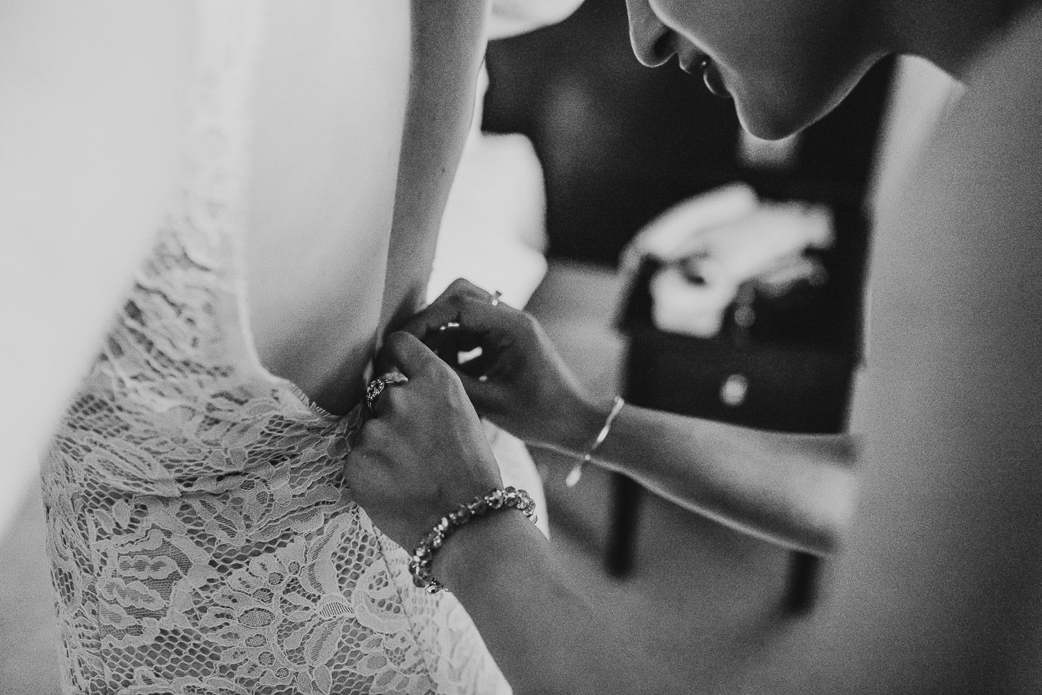 bridesmaid helping bride with wedding dress